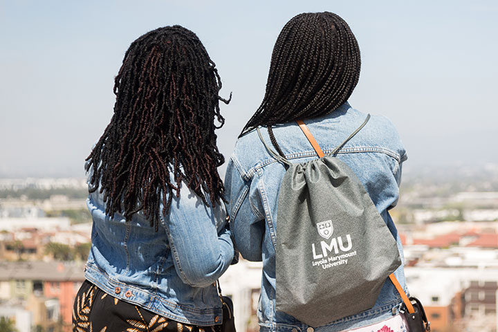 A student with an LMU branded backpack looking out across the bluff with their parent