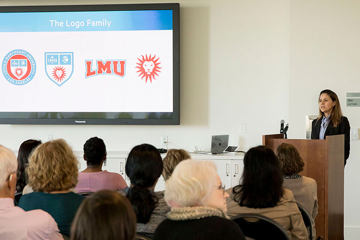 A training session with a speaker explaining the identity system on a screen in front of a large seated group