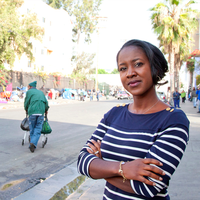 Woman with crossed arms near homeless encampment