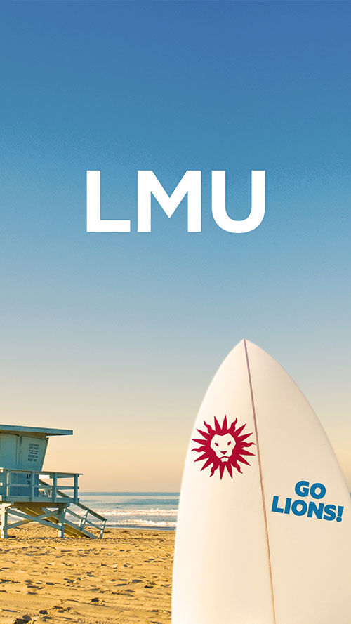 A surfboard sticking out of sand with a Spirit Mark sticket, with the beach, ocean, and a lifeguard shack in the background and LMU logo above