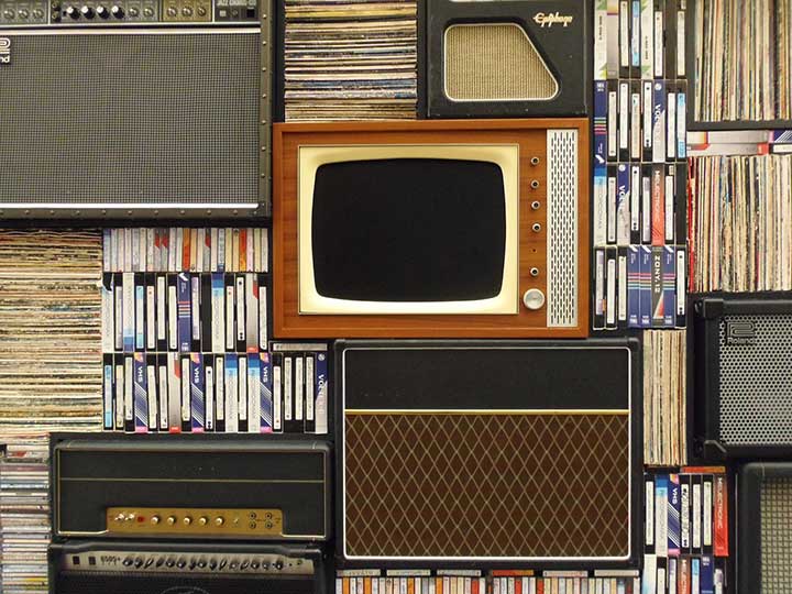 Stacks of old televisions, amps, speakers, records, and VHS tapes