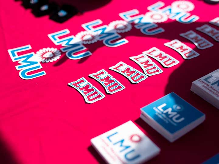 A table with various stickers, cards, badges, and other items with LMU branding