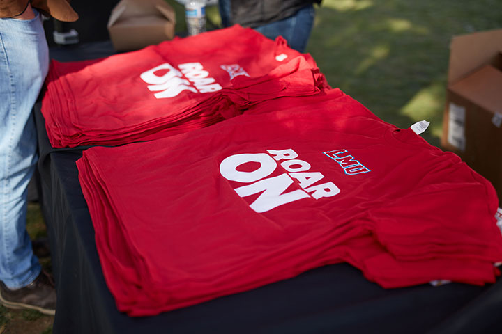 LMU t-shirts with the words Roar On stacked on a table