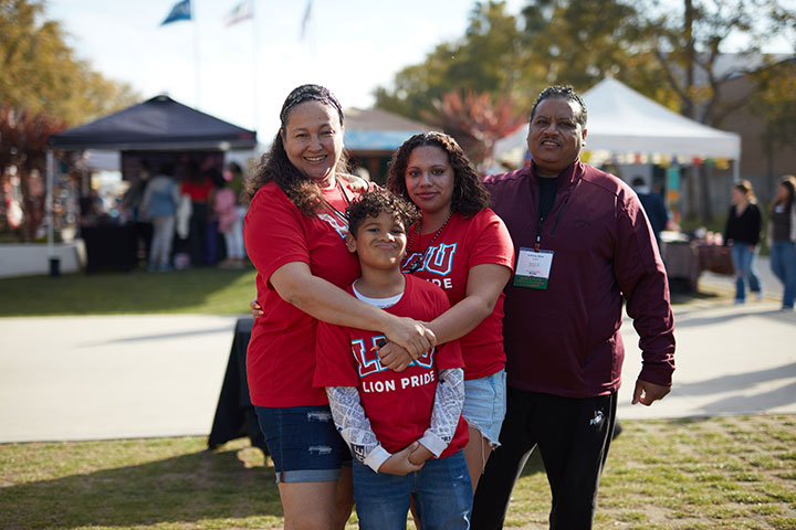 An LMU student, their parents, and their younger siblings wearing t-shirts with the words Lion Pride